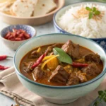Beef rendang served with rich coconut sauce and spices, garnished with fresh herbs.